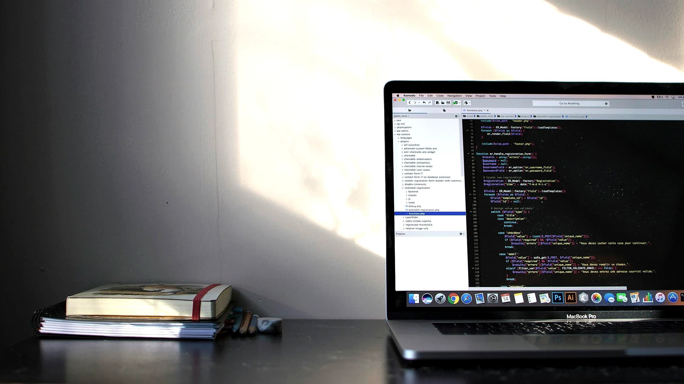 A laptop on a desk showing an editor with code, next to a notebook and a cup of coffee